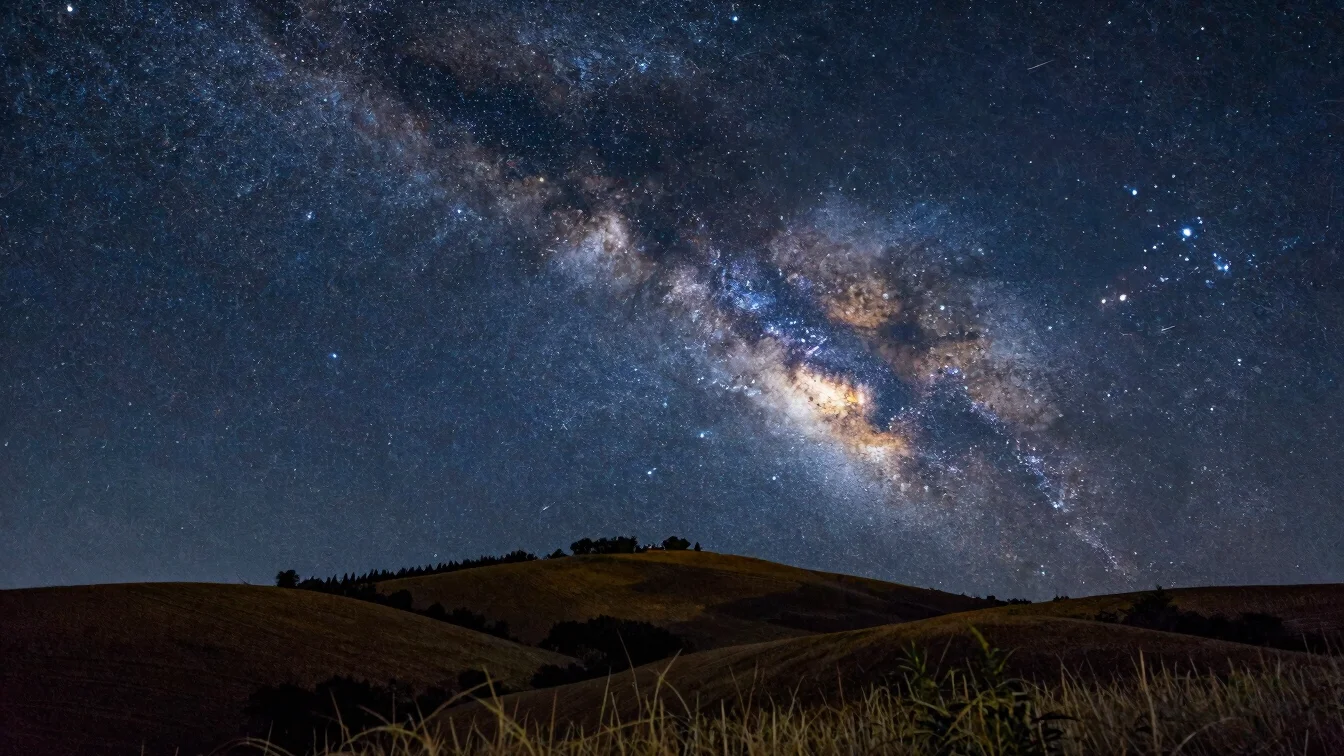 Summer Milky Way above a French hillside, Lyra and Cygnus visible, dark midnight blue sky, restrained detail, no artific