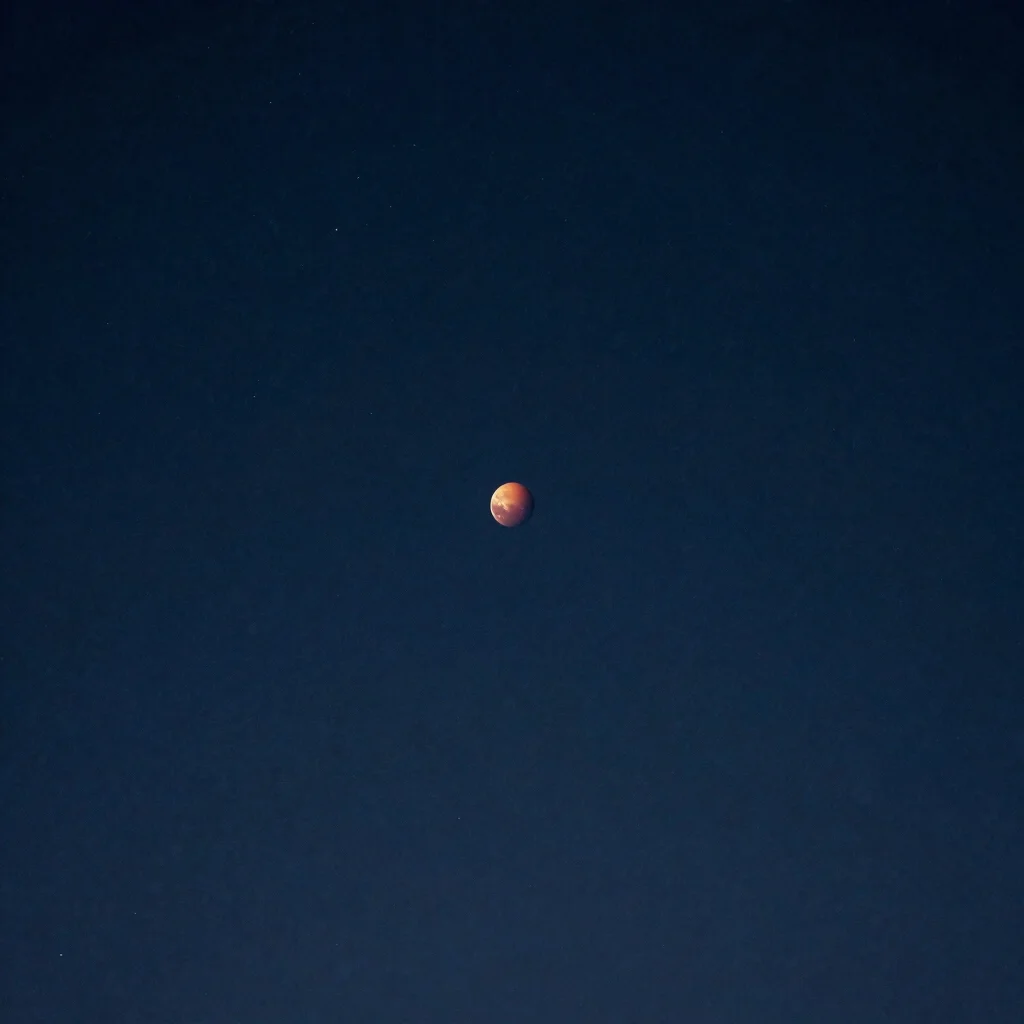 Astronomy photograph of Mars near opposition showing a small reddish disk, natural night-sky darkness, no text